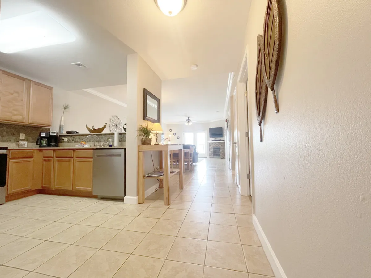 A wide-angle view showing the kitchen area, dining space with a table and chairs, entrance to the living room, and tasteful decorative wall art. The layout is open, with ample natural light and inviting decor.