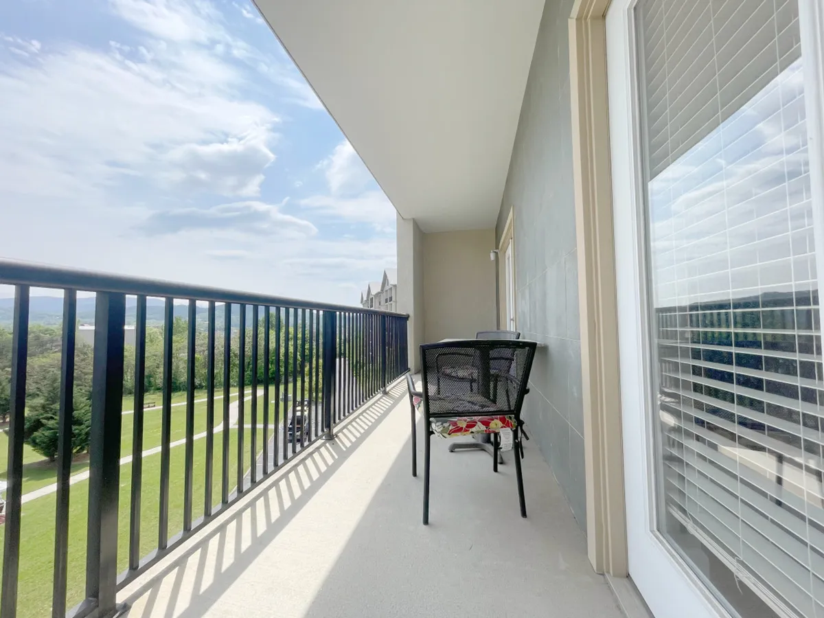An exterior balcony scene with comfortable chairs overlooking a tranquil natural landscape. The balcony setting suggests relaxation with a view, a place to unwind after a busy day of exploring local attractions.