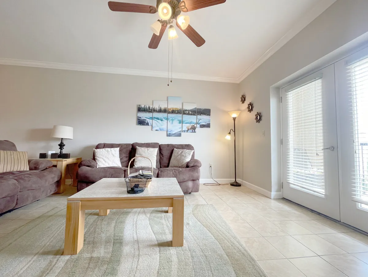 A cozy den with a comfortable sofa, coffee table, lamp, and decorative wall art. The inviting setup makes it ideal for relaxing, socializing, or accommodating extra guests with a sleeper sofa.