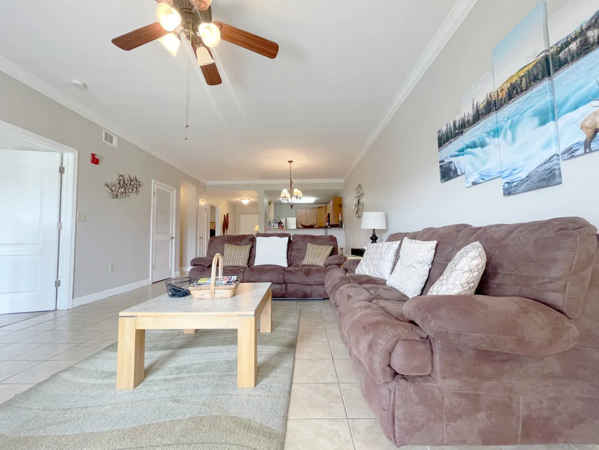 A welcoming living room featuring comfortable sofas arranged around a coffee table, with tasteful artwork on the walls. The space is clearly open and inviting, ideal for gatherings or relaxing with family, and the furniture appears to be arranged to allow easy mobility.