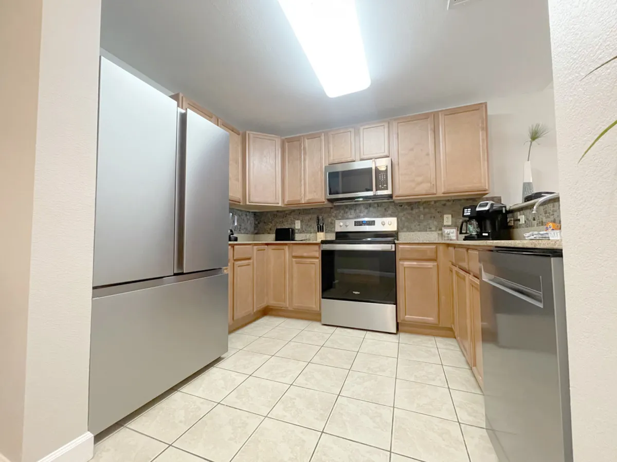 A modern kitchen with stainless steel appliances, granite countertops, and wood cabinetry. The area is spacious, allowing for effortless movement and inclusive meal preparation, whether for family gatherings or casual cooking.